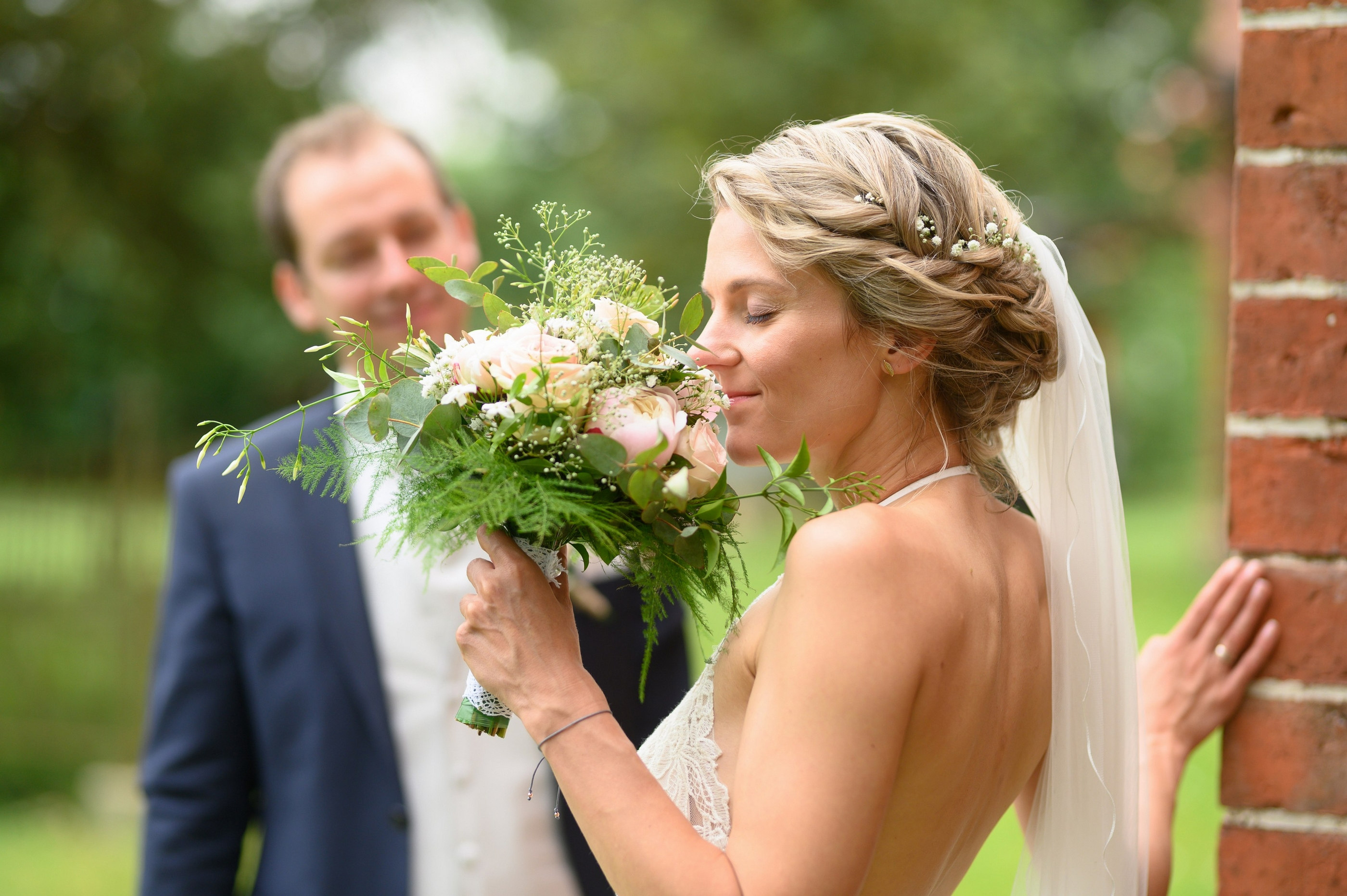 Braut riecht an Brautstrauß aus Rosen, Gartenkulisse — Holger Martens