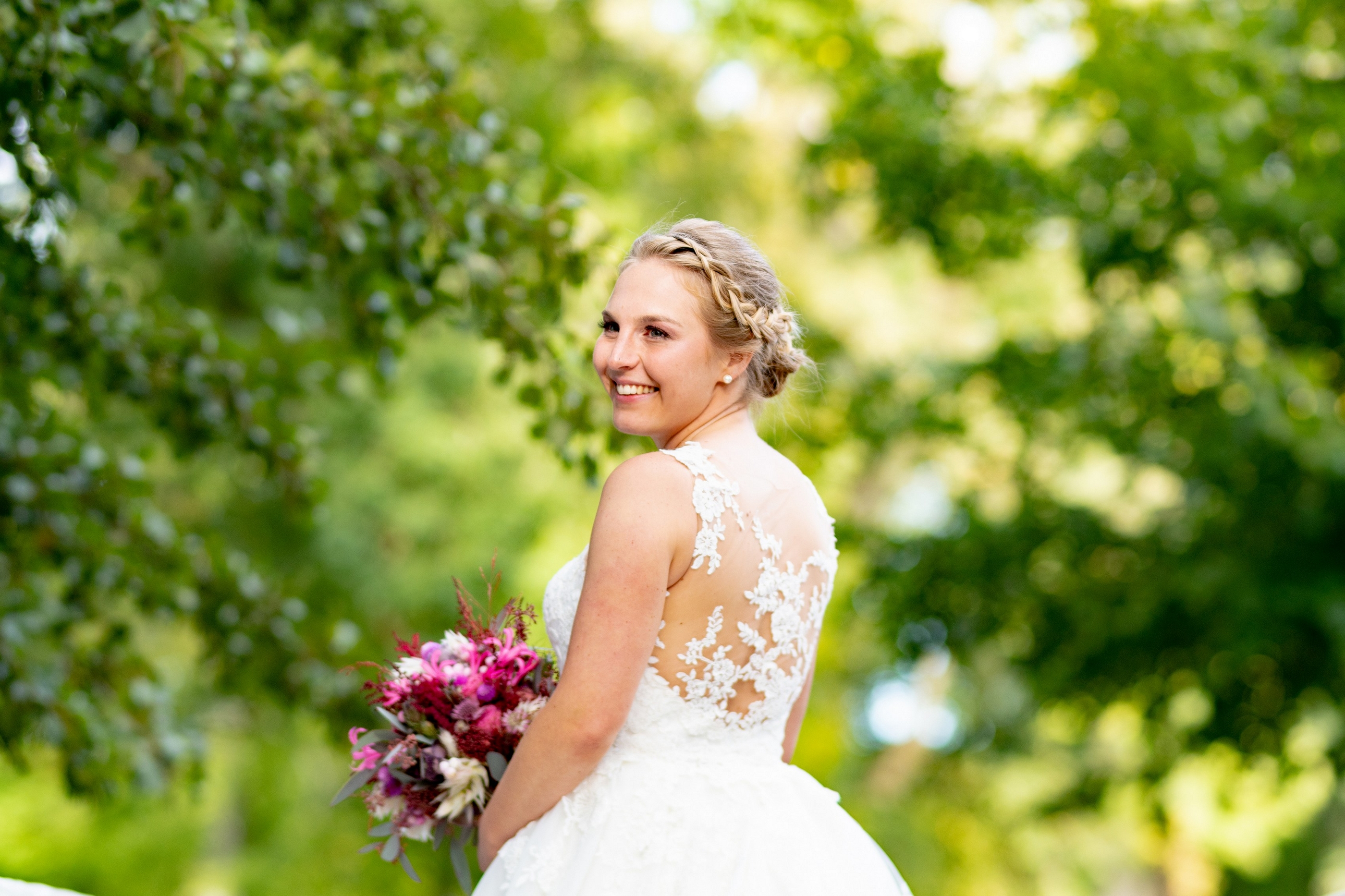 Braut mit Spitzenrücken und Brautstrauß im Garten — Holger Martens