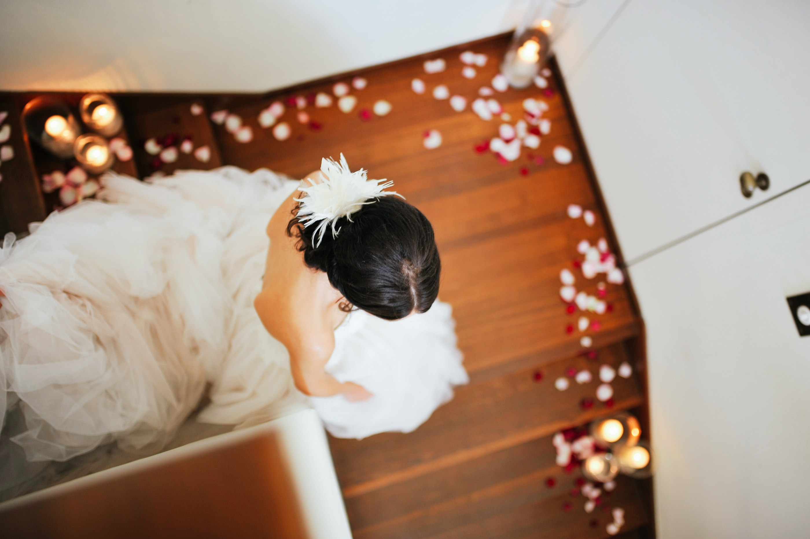 Braut im Tüllkleid umgeben von Rosenblättern und Kerzenlicht — Holger Martens