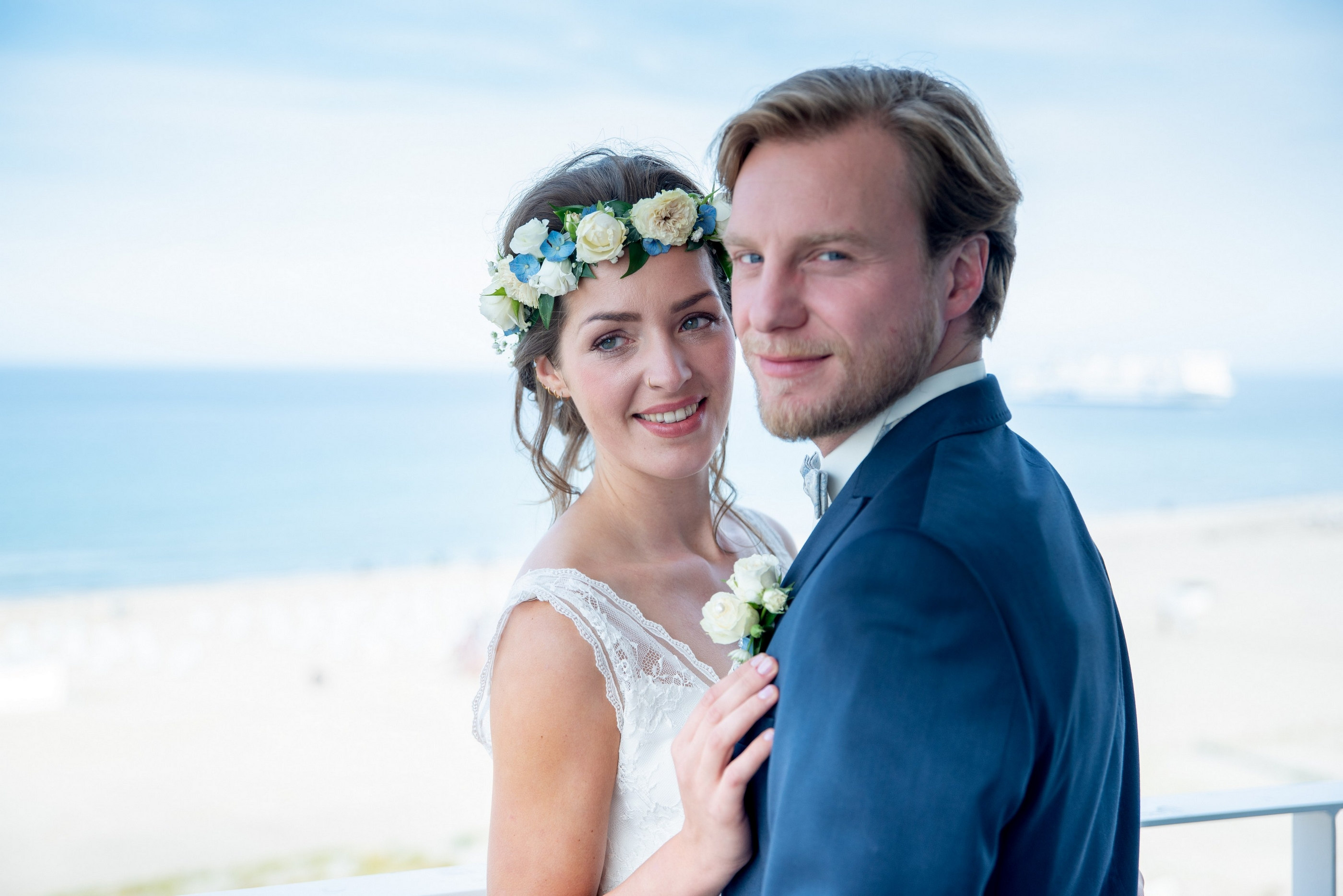 Brautpaar am Strand mit Blumenkranz, Meer im Hintergrund — Holger Martens