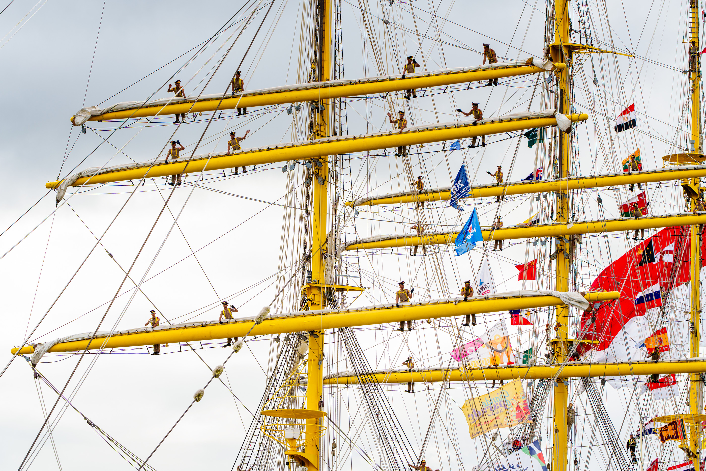 Crew-Mitglieder bei der Arbeit an den gelben Masten eines Großseglers — Hanse Sail Rostock — Holger Martens